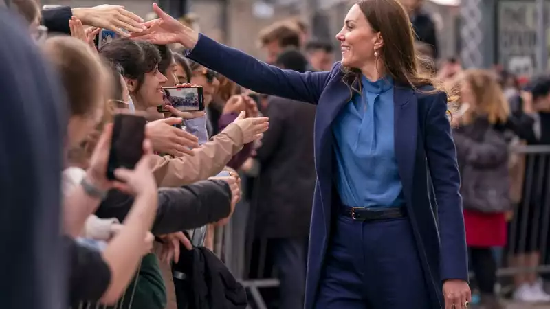 Kate Middleton helps a student find the answer to a crossword question about the queen.