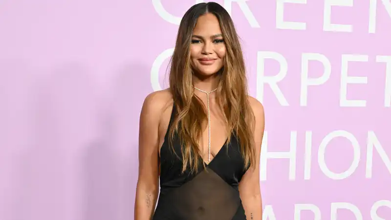 Chrissy Teigen's bare dress is coated with a sheer panel.