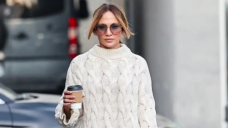 Jennifer Lopez stacks a cable knit sweater, Ugg, and a rare, Holiday80,000 birkin like a holiday Rom-Com character